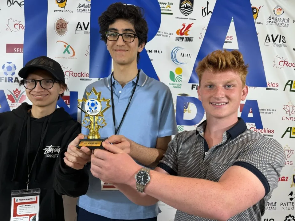 FIRA robotics team members with their autonomous race car and competition trophy